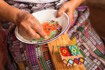 January 20, 2015 San Pedro la Laguna, Guatemala: closeup of the hands of a mayan woman selecting small glass beads with a needle for handicraft
