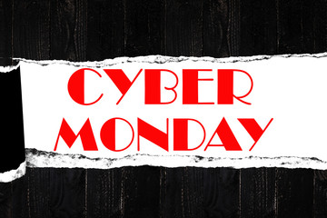 cyber monday on open ripped paper,black wooden plank background.