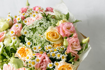 beautiful bouquet of mixed flowers into a vase on wooden table