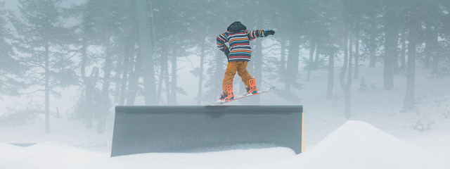 Skier doing snowboarding using a ramp