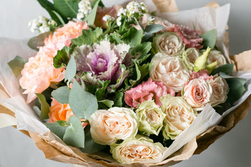 beautiful bouquet of mixed flowers into a vase on wooden table