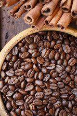 Close up of coffee beans in wooden bowl and cinnamon for background