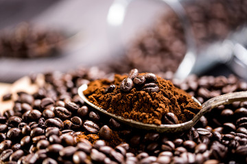 Coffee poured into an ancient antique silverware spoon. Around the spoons scattered coffee beans.