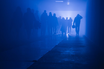 Fototapeta na wymiar silhouette of people going to work walking in a tunnel in smoke against a background of bright light. mysterious mood