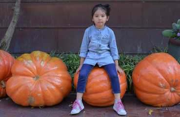 Little girl sitting on a big pumpkin , filtered tones