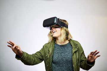 young woman wearing virtual reality goggles white background