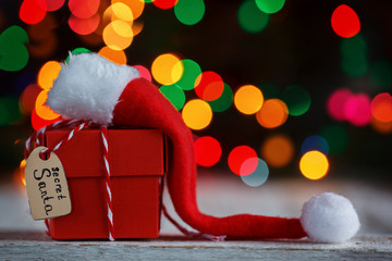 Christmas present or box for secret santa with Santa hat. Greeting card.
