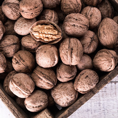 Walnut kernels and whole walnuts on rustic old wooden table