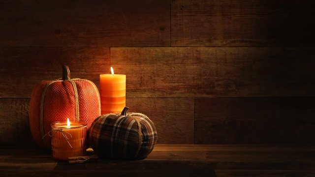 This is a close-up video symbolizing Thanksgiving, fall, autumn, using a still life embroidered Pumpkin setting inside a barn background made up of old red wood.