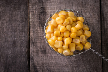 Sweet corn kernels in bowl on wooden table . Cooked canned yellow vegetable, vegetarian staple food.