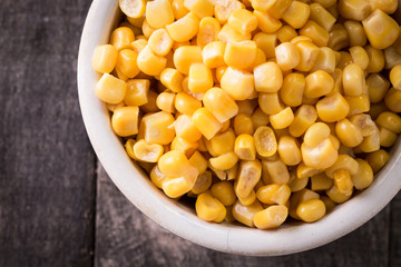 Sweet corn kernels in bowl on wooden table . Cooked canned yellow vegetable, vegetarian staple food.