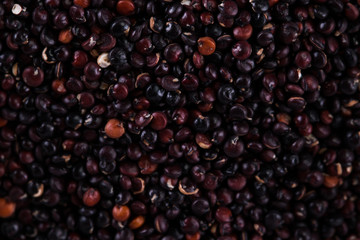 Red, black and white quinoa seeds on a wooden background