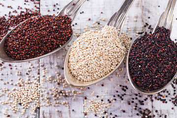 Red, black and white quinoa seeds on a wooden background