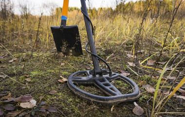 Treasure searching with metal detector and shovel on the stubble field