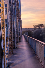 Walkway on the old metal bridge during sunset