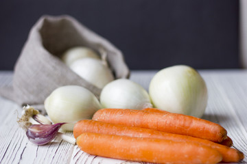 onions and carrots on wooden background. the concept of food