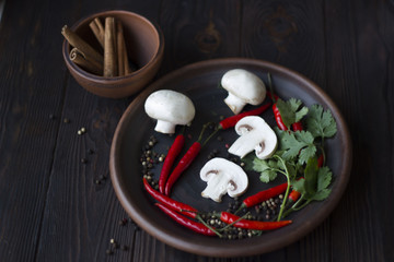 mushrooms with spices, cinnamon, red pepper on a plate on wooden background, concept food