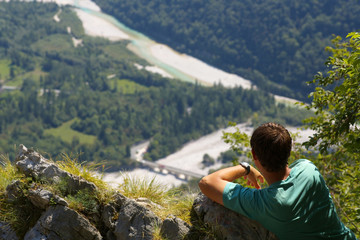 Naklejka premium Resting man watchig a valley of Soca river, Slovenia