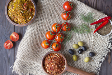 Vegetables and spices in a wooden table. tomatoes, olives, chili and spices close up.