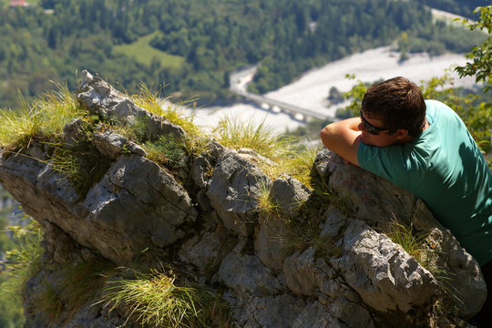 Resting man leaning against a rock with a valley on backroud, Slovenia