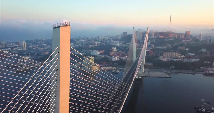 Amazing aerial view of the Zolotoy Bridge (the Golden Bridge, built in 2012) that is cable-stayed bridge across the Zolotoy Rog harbour. Vladivostok is on the background. Russia. Autumn sunrise