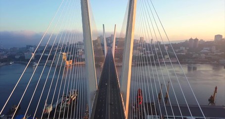 Descending above the road between stay cables of Zolotoy Bridge (Golden Bridge, cable-stayed bridge across Zolotoy Rog harbour built in 2012). Aerial view of cars driving across it. Vladivostok,Russia - Powered by Adobe