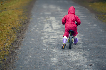 Obraz premium cute little girl riding run bike in the forest