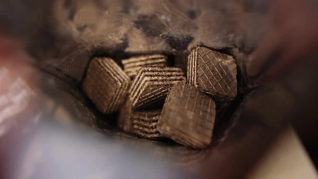 Waffles inside shiny foil packaging. High-calorie food. Slow motion. Selective focus.