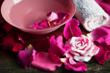 Obraz na płótnie Canvas Bowl with water and rose petals on wooden table