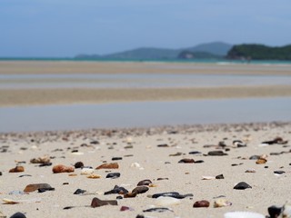 Colorful gravel on the sand, blurred background beach and sea.