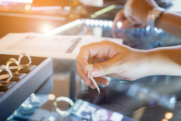Asian woman choosing wedding rings at jewelry diamond shop