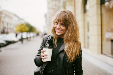 Portrait of a beautiful girl on the street, holding a paper cup