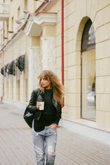 Portrait of a beautiful girl on the street, holding a paper cup