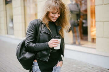 Portrait of a beautiful girl on the street, holding a paper cup