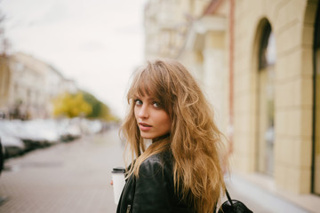 Portrait of a beautiful girl on the street, holding a paper cup
