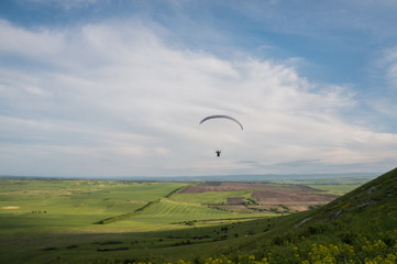 Paraglider flying above field