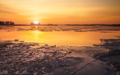 Winter landscape with frozen lake and sunset sky. Composition of nature.