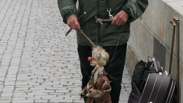 The puppet master directs the doll on the street which plays a musical instrument in anticipation of coins, manipulation
