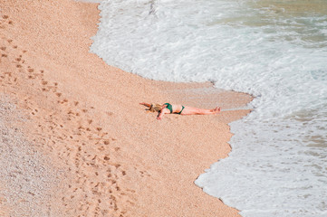 Young woman in bikini lying on the beach under the bright sun - Kaputas beach