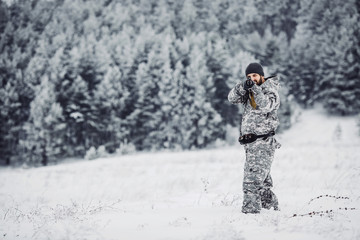 Male hunter in camouflage looking for his target or prey .Winter scene