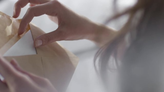Mid-section of unrecognizable woman opening and reading handwritten letter from lover