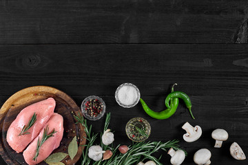 Fototapeta na wymiar Raw chicken breast fillets on wooden cutting board with herbs, spices, mushrooms and chili peppers. Top view with copy space