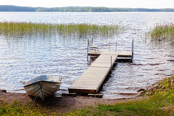 Jetty and boat are on lake in summer day