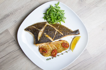 Fried flounder with zucchini, tomatoes and arugula. Close-up, selective focus.