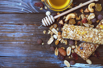 Cereal bars with nuts, seeds and dried fruits on the wooden table, with copy space. Flat lay.
