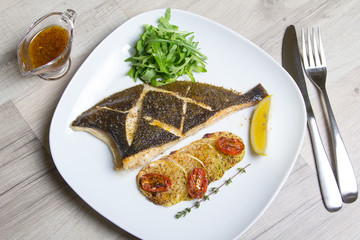 Fried flounder with zucchini, tomatoes and arugula. Close-up, selective focus.