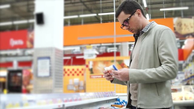 Young man looking over the packages with precooked food in the section with frozen products
