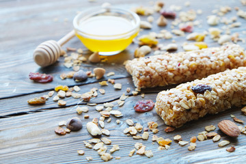 Healthy granola bars with fruits, nuts and honey on wooden background.