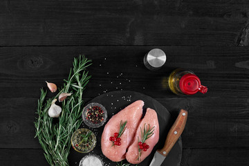 Raw chicken fillet with cooking ingredients on black slate table. Food background. Top view, copy space.