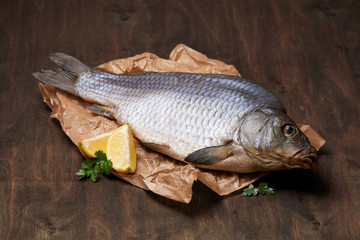 Dried carp with lemon and greens on the crumped paper